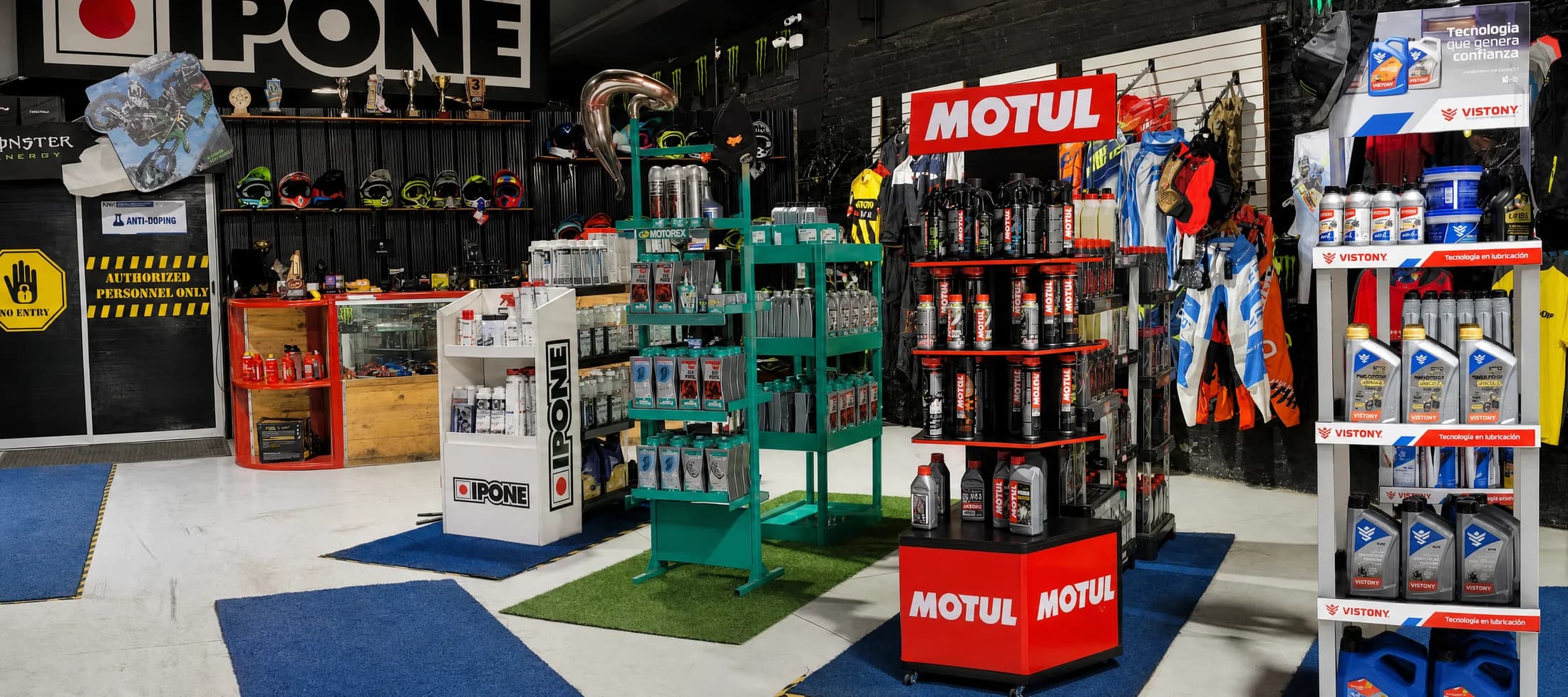 Sector de lubricantes de Proride con exhibidores oficiales de IPONE, Motorex, Motul y Vistony, y muro de indumentaria al fondo