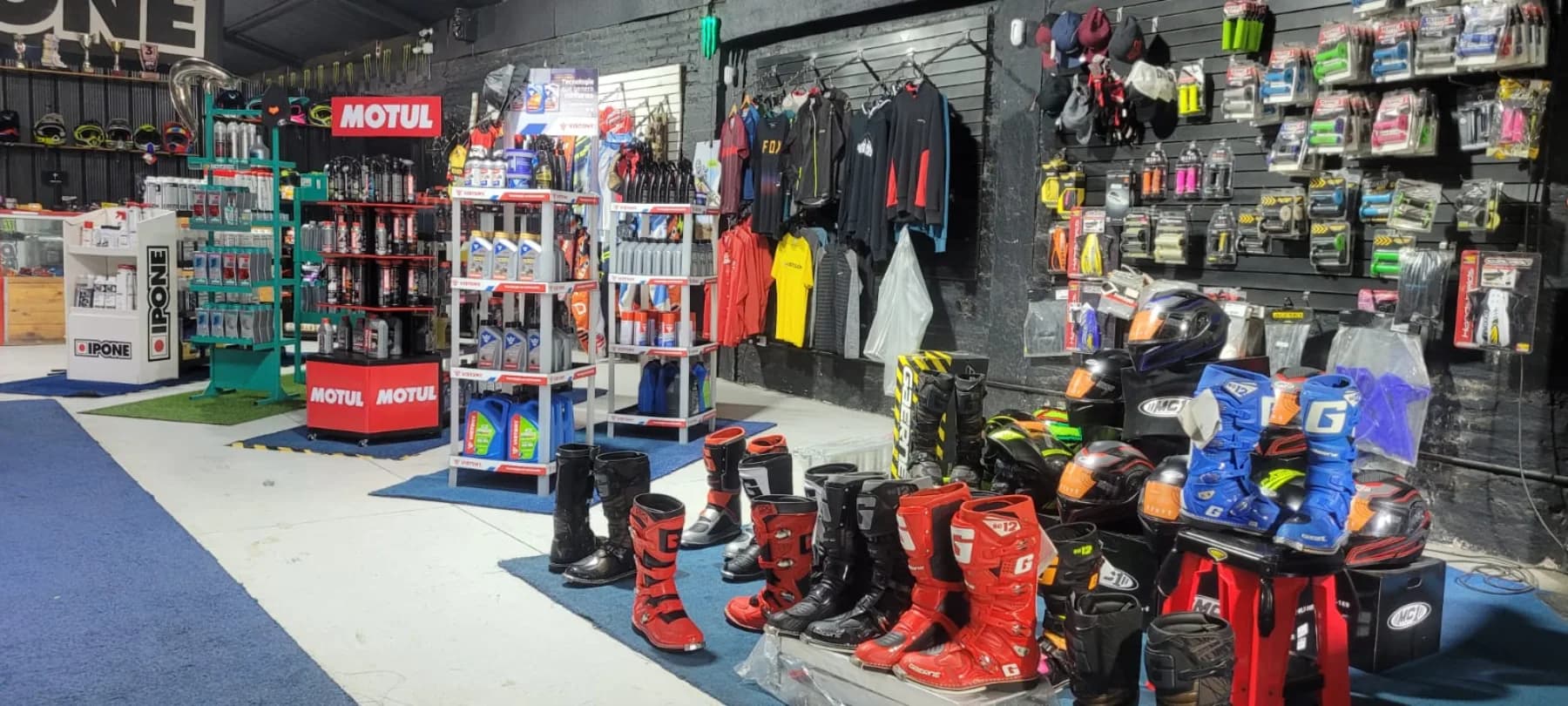 Muro de accesorios de Proride con guantes, cascos, lubricantes y repuestos exhibidos en estantería